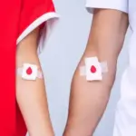 Braccia di due donatori con cerotto personalizzato con il disegno di una goccia