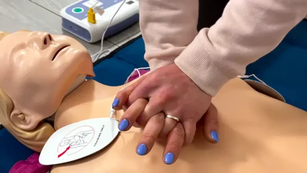 laico durante un corso BLSD che effettua massaggio cardiaco di addestramento con un defibrillatore collegato ad un manichino