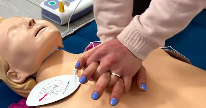 laico che effettua massaggio cardiaco di addestramento con un defibrillatore collegato ad un manichino