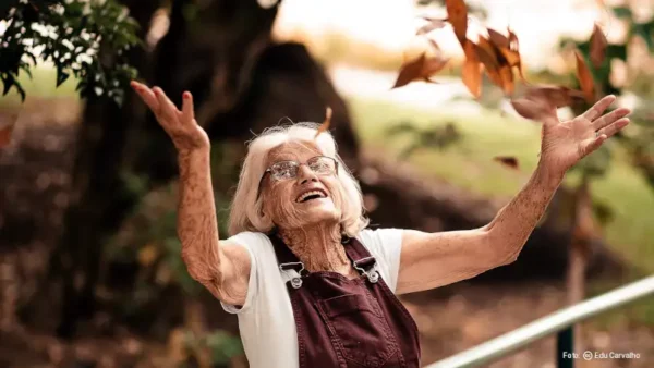 Signora anziana giova con le foglie in autunno foto di Edu Carvalho