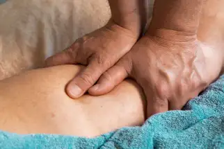 mani di uno specialista di osteopatia durante la manipolazione di una gamba