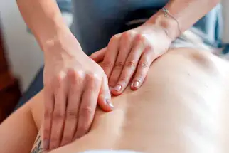 mani di uno specialista di osteopatia durante la manipolazione della zona lombare
