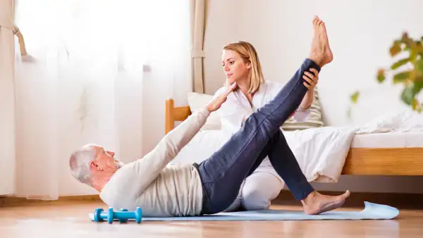 anziano e fisioterapista durante una sessione di fisioterapia domiciliare