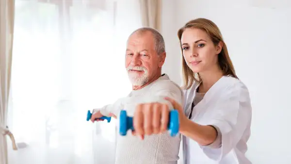 Anziano e fisioterapista durante una sessione di fisioterapia domiciliare